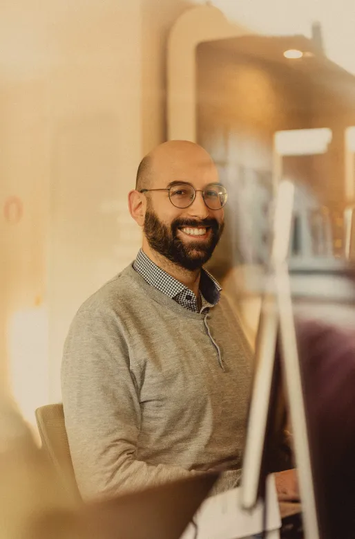 Photo de Victor, souriant, assis à un bureau.